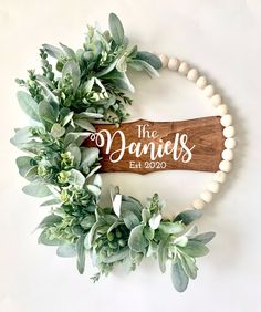 a wooden sign that says the daniels est 2009 hanging on a wall with greenery around it