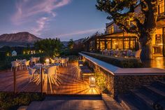 an outdoor patio with tables and chairs lit up at night in front of a mountain