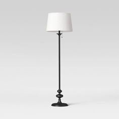 a black floor lamp with a white shade on it's top and bottom part