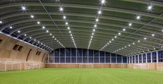 an indoor soccer field with lights on the ceiling and grass in the foreground at night