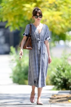 a woman walking down the street wearing sunglasses