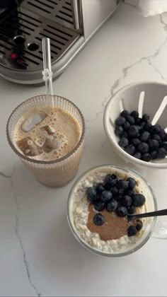 two bowls of oatmeal with blueberries next to a blender and toaster