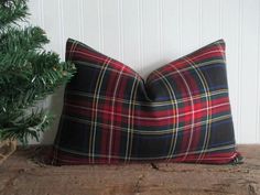 a plaid pillow sitting on top of a wooden table next to a potted plant