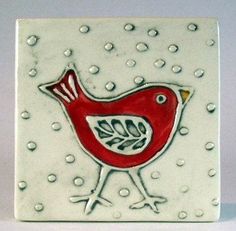 a red bird is sitting on top of a white square tile with water droplets around it