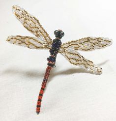 a beaded dragonfly sitting on top of a white table next to a wall