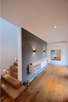 an empty living room with stairs leading up to the second floor and light fixtures on the wall