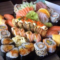 an assortment of sushi on a black platter