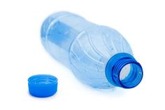 a plastic water bottle with a blue lid and an empty cup next to it on a white surface