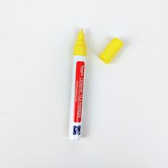 a tube of yellow marker sitting on top of a white surface