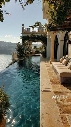 an outdoor swimming pool with chaise lounges next to it and the ocean in the background