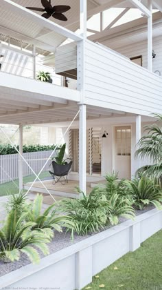 a white house with some plants in front of it and a ceiling fan on the roof