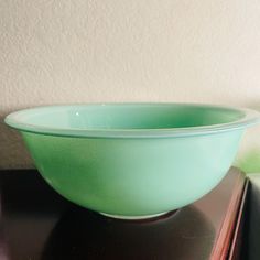 a green bowl sitting on top of a wooden table