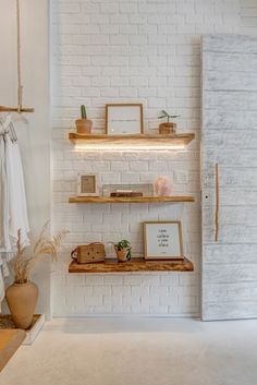 a white brick wall with wooden shelves and pictures on the ledges in front of it