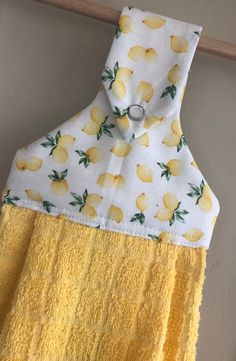 a yellow towel hanging from a hook on a clothes line with lemons printed on it