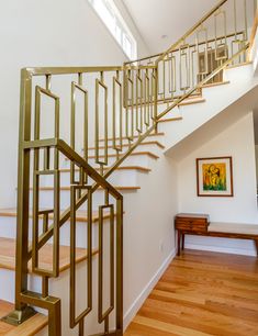 a stair case in a house with wood floors and white walls, along with a painting on the wall