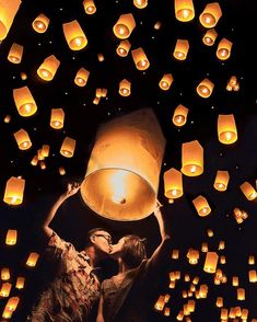 two people kissing in front of lanterns floating in the air at night, with one person holding a lantern up to their face