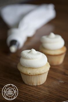 two cupcakes with white frosting sitting on a table