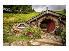 a hobbot house with a red door surrounded by greenery