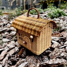 a wicker purse sitting on the ground in front of some rocks and grass,