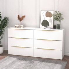 a white dresser with two plants on top