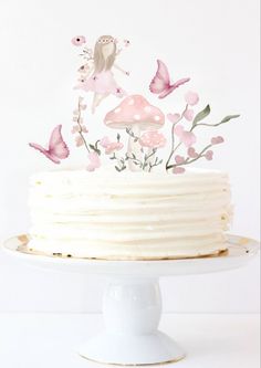 a white cake with pink flowers and butterflies on top, sitting on a pedestal in front of a white wall