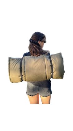 a woman in shorts is holding a large pillow on her back and looking at the sky