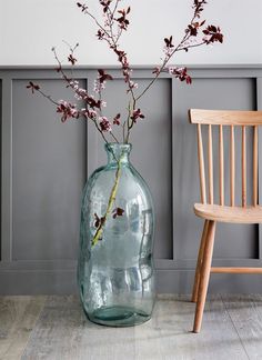 a vase filled with flowers sitting on top of a wooden floor next to a chair