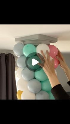 someone is placing balloons on the top of a column to make it look like they are floating