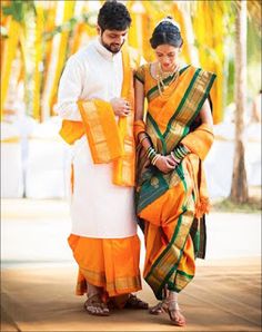 a man and woman dressed in orange and green sari standing next to each other