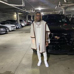 a man standing next to a black car in a parking garage with other cars behind him