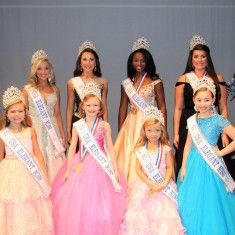 a group of young women standing next to each other wearing dresses and tiaras on their heads