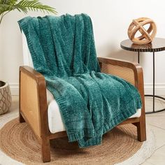 a chair with a green blanket on top of it next to a potted plant