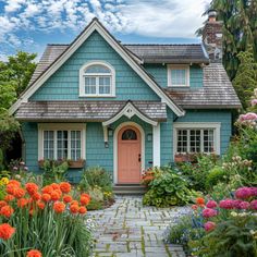 a blue house surrounded by colorful flowers and greenery