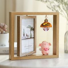 a small pig figurine sitting in front of a frame with a lamp hanging from it