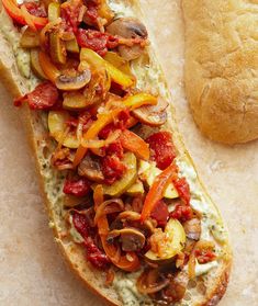 a sandwich with tomatoes, mushrooms and cheese on it next to a baguette