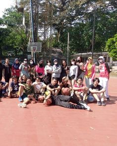 a group of people standing and sitting on top of a tennis court next to each other