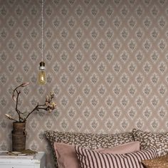 a bed sitting under a light fixture next to a wall with a flower vase on top of it