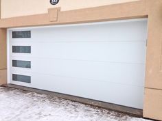 a large white garage door on the side of a building with snow on the ground