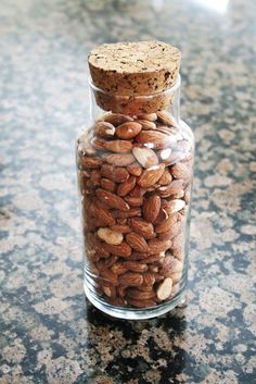 a glass jar filled with almonds on top of a counter