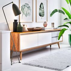 a living room with white walls and plants on the sideboard in front of it