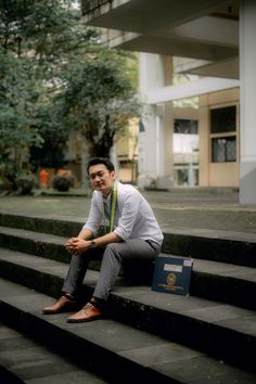 a man sitting on some steps with his hand in his pocket and looking at the camera