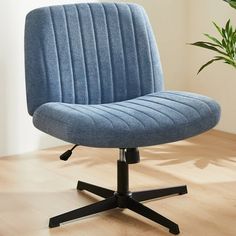 a blue office chair sitting on top of a wooden floor next to a potted plant