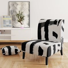 a black and white chair sitting on top of a hard wood floor next to a potted plant