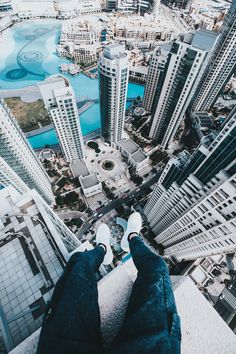 a person standing on top of a tall building with their feet up in the air