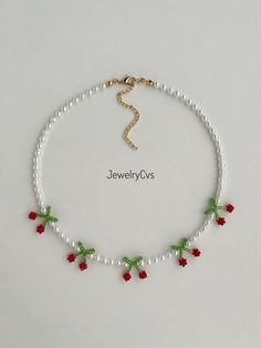 a white beaded necklace with red and green beads