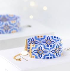 a blue and white bracelet with gold accents on it sitting on top of a box