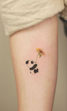 a small panda holding a sunflower tattoo on the right side of the leg,