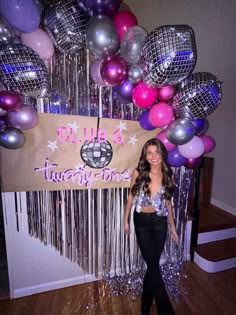 a woman standing in front of a sign and balloons