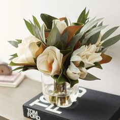 a vase filled with flowers sitting on top of a table next to a black book