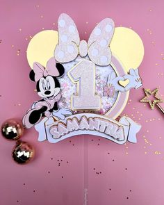 a minnie mouse 1st birthday cake topper on a pink background